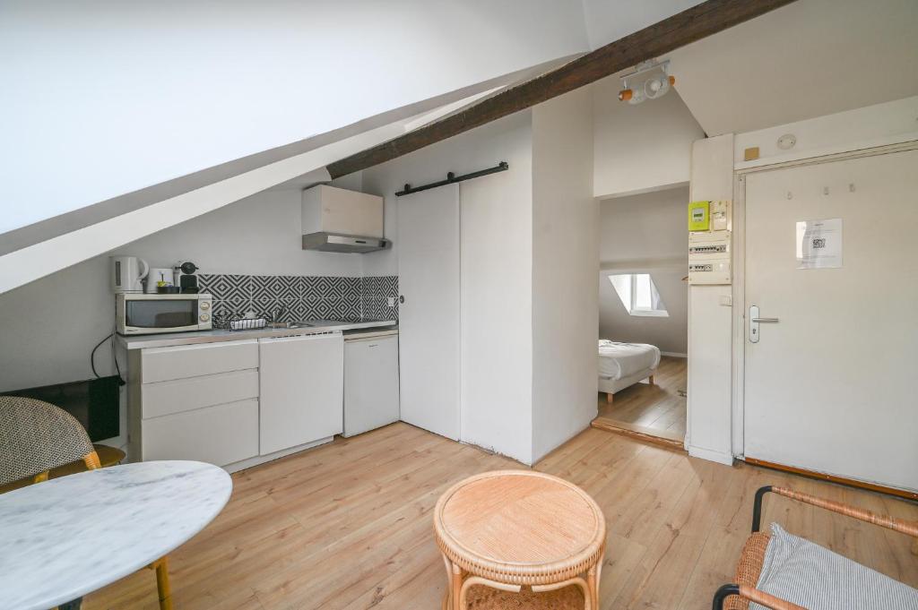 une cuisine avec des armoires blanches et une table et des chaises dans l'établissement Cléry 57, à Paris