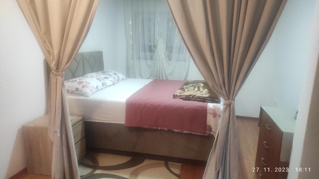 a small bed with curtains in a room at Nevesinje centar Apartman in Nevesinje