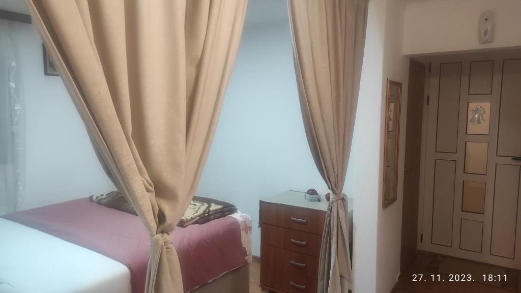 a bedroom with a bed and a curtain and a dresser at Prenoćiste Nevesinje in Nevesinje