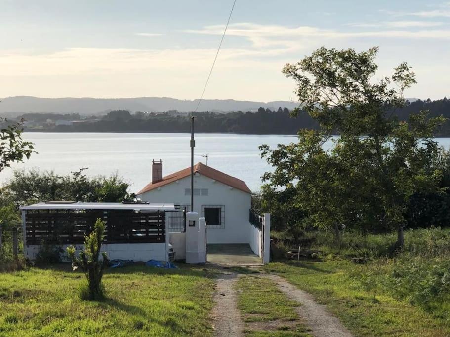 ein kleines weißes Gebäude neben einem Wasserkörper in der Unterkunft Casa a la orilla del mar in Neda