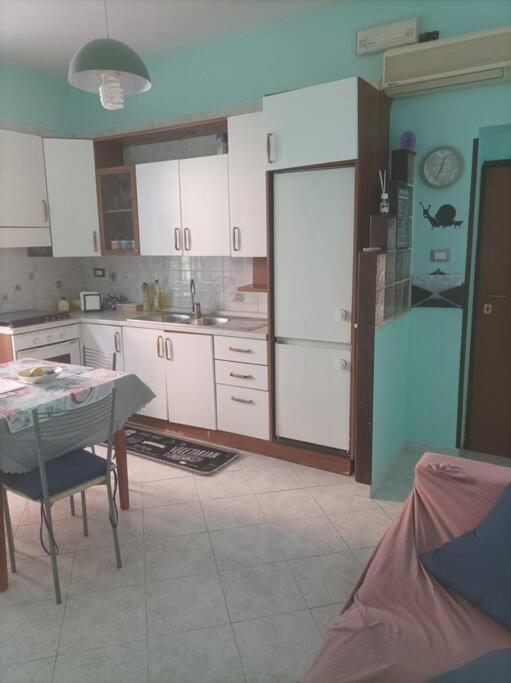 a kitchen with white cabinets and a table and a dining room at Licheni house in Rome