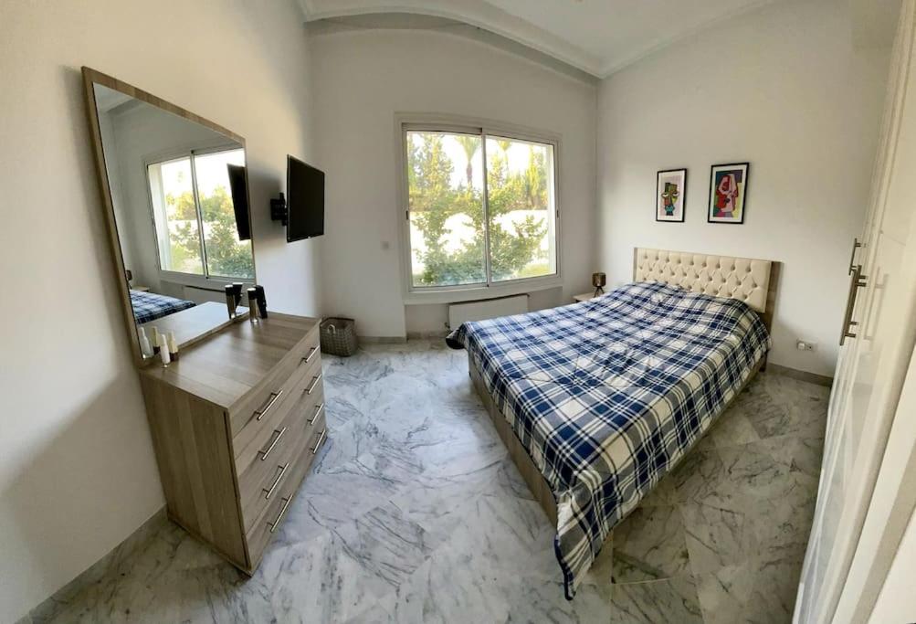 a bedroom with a bed and a dresser and a mirror at Appart Cosy pieds dans l'eau au coeur de Kantaoui in Sousse