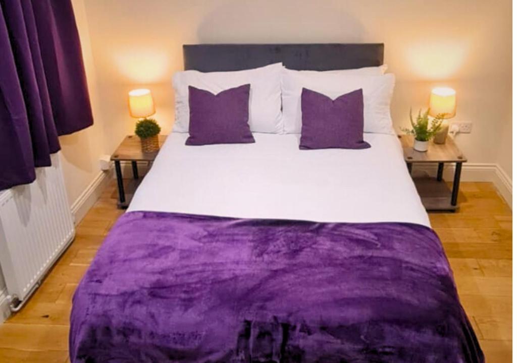 a bedroom with a large bed with purple sheets and pillows at Furley Road London Guest House in London