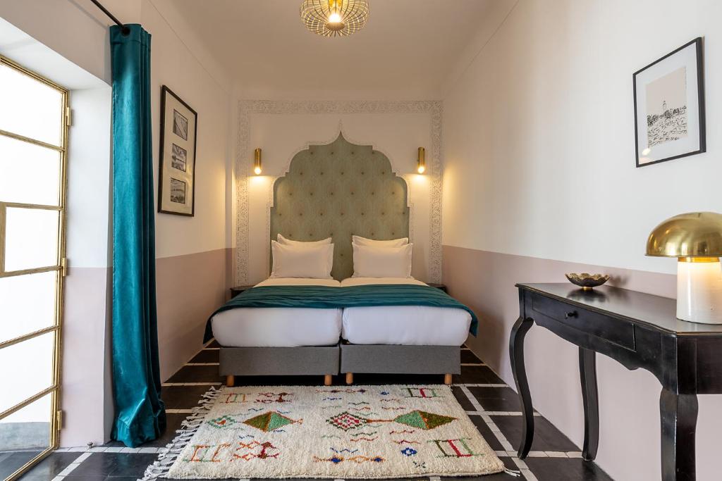 1 dormitorio con cama y mesa con alfombra en Riad la Parenthèse by Sashema en Marrakech