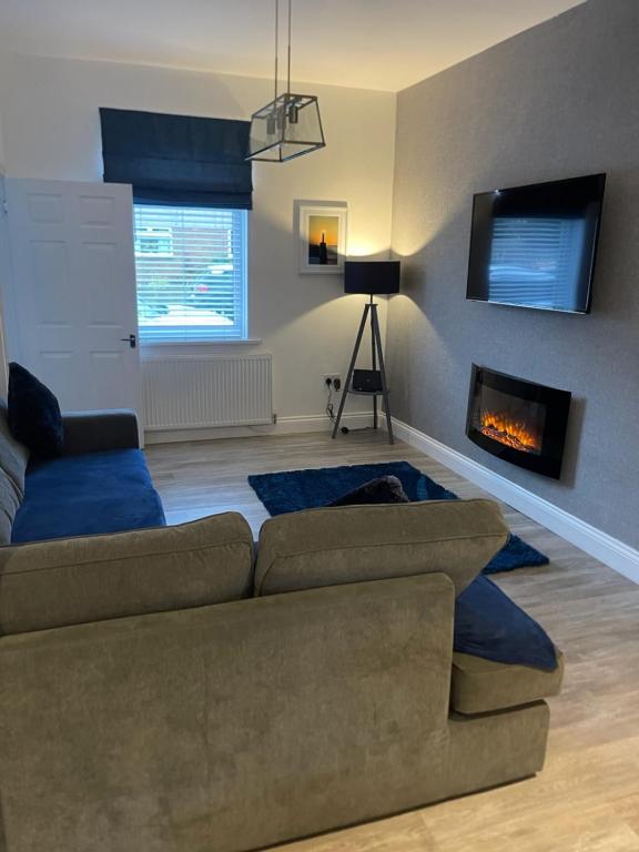 uma sala de estar com um sofá e uma lareira em Oyster Retreat em Amble