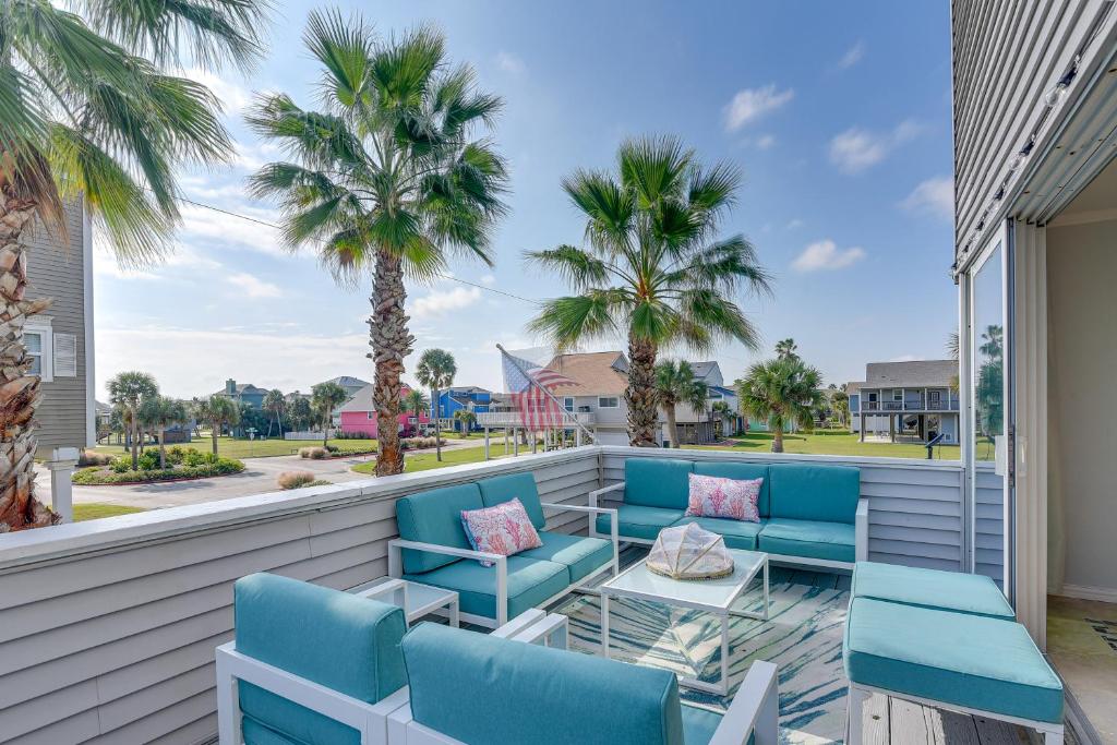 a patio with blue chairs and a table and palm trees at Luxury Galveston Retreat - Walk to Pirates Beach! in Galveston