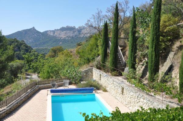 a blue swimming pool in a yard with trees at Aux Dentelles in La Roque-Alric