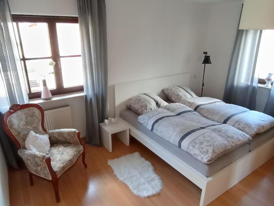 um quarto com uma cama, uma cadeira e uma janela em Ferienwohnung Marell em Großwallstadt