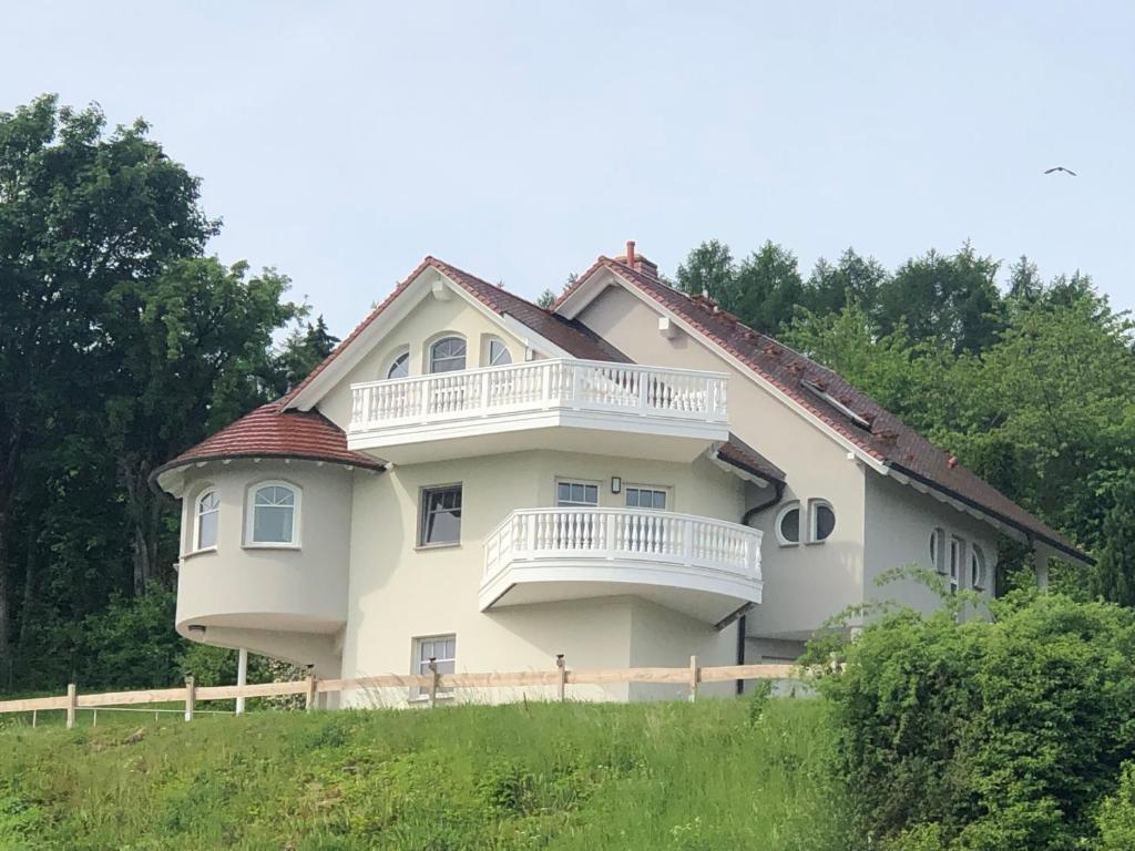 a large white house with a balcony on a hill at Ferienwohnung Graswald mit Panoramablick in die Rhön in Kaltennordheim