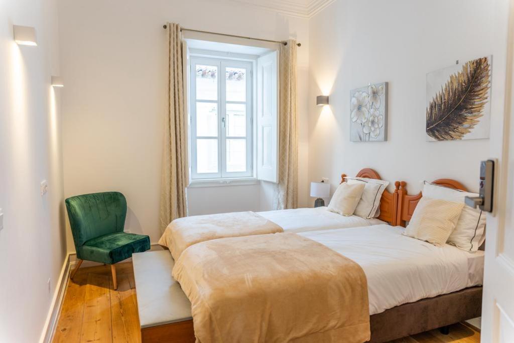 1 Schlafzimmer mit 2 Betten und einem grünen Stuhl in der Unterkunft Guest House - Palácio Diana in Évora