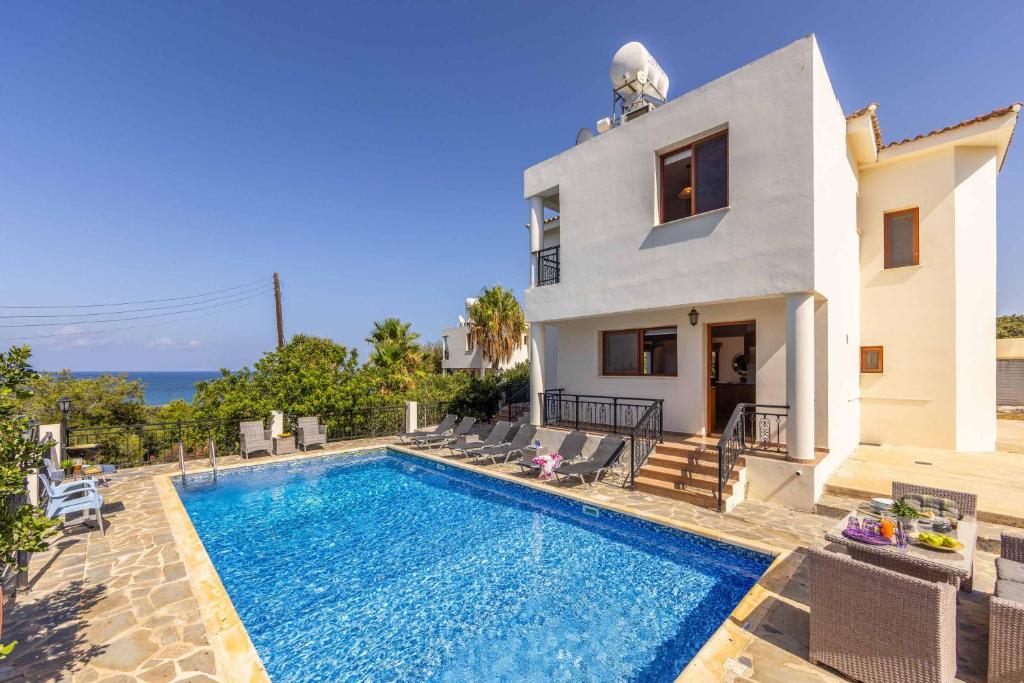 a villa with a swimming pool in front of a house at Villa Marilia in Neo Chorio