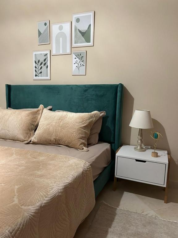 a bed with a green headboard and a table with a lamp at formidable S2 près du carrefour in La Marsa