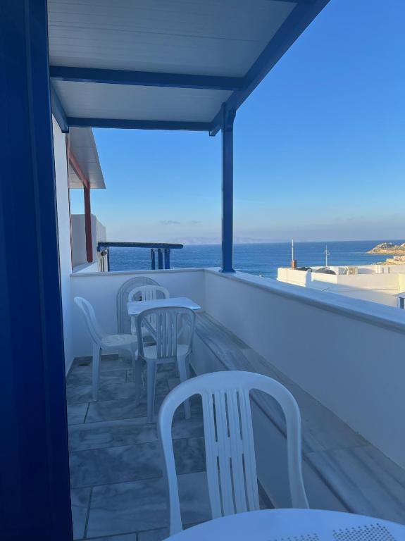 a balcony with chairs and tables and the ocean at Sea views - Marble Palace - 2 floors in Tinos