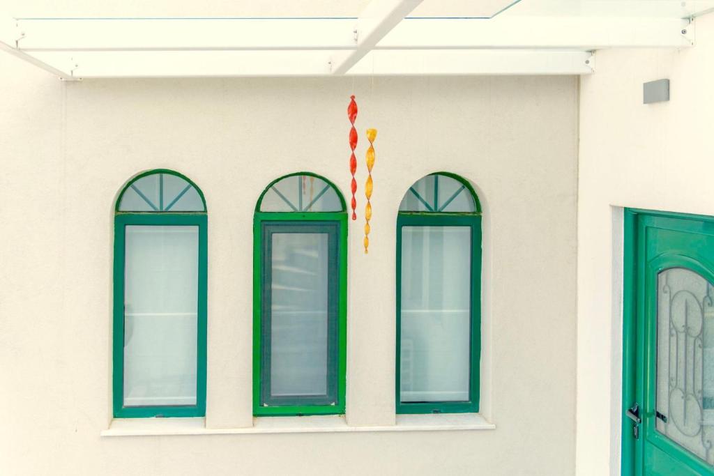 a white building with green windows and a flag at Villa Murtal in Gerani