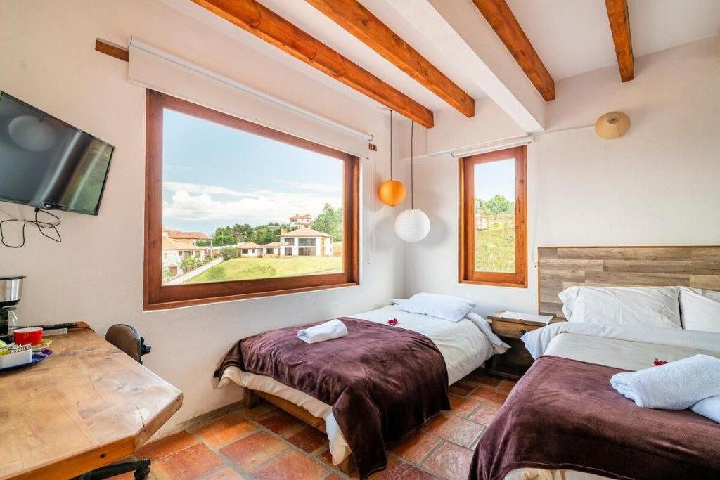 a bedroom with two beds and a large window at Habitación privada - Villa Luz in Villa de Leyva