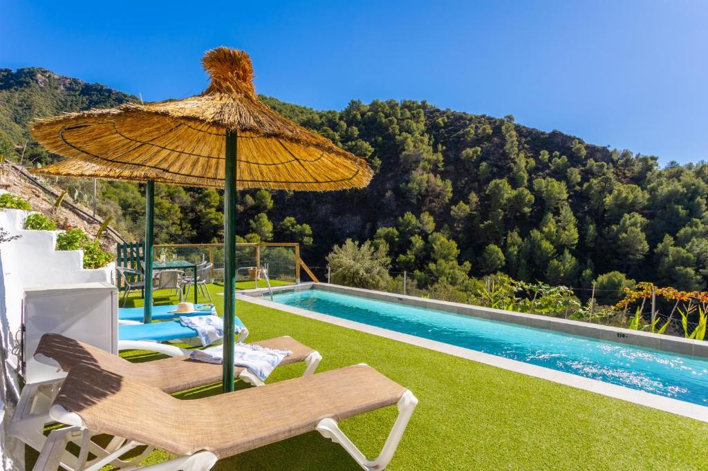 a patio with a umbrella and a swimming pool at Villa Flower in Cómpeta