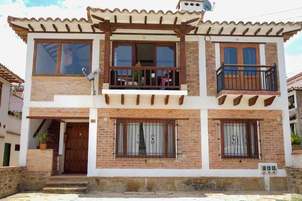 ein Backsteinhaus mit Fenstern und einem Balkon in der Unterkunft VILLA CHARLOTTE 1 en colombia in Villa de Leyva