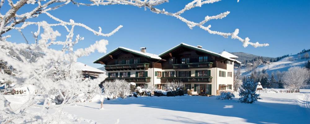 ein großes Haus im Schnee mit schneebedeckten Bäumen in der Unterkunft Pension Kreuzer in Flachau