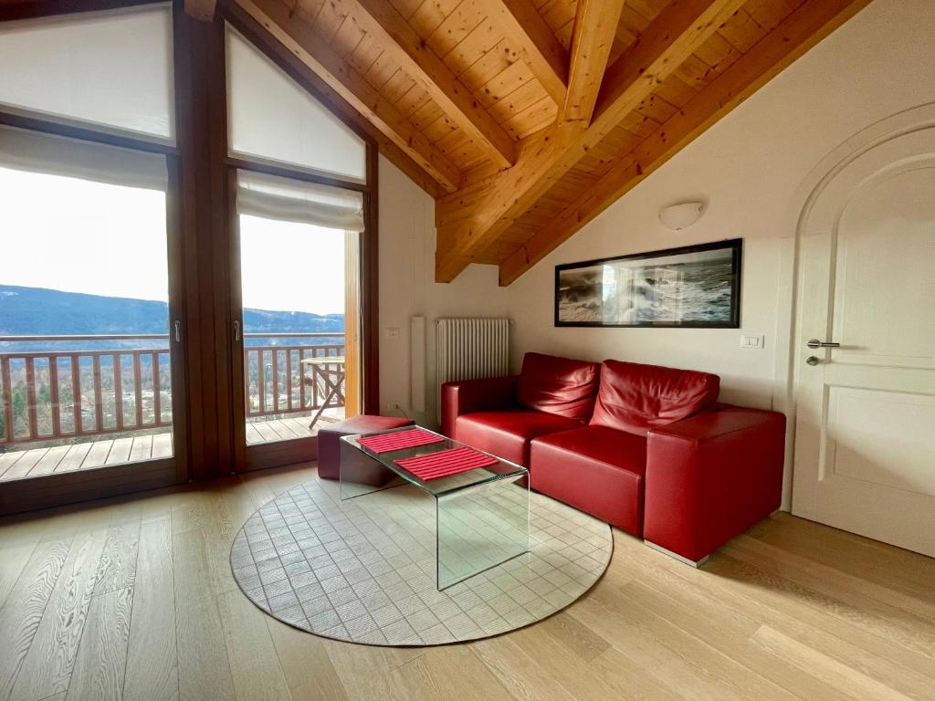 a living room with a red couch and a table at Trilo Riflessi d'Alpe in Lavarone