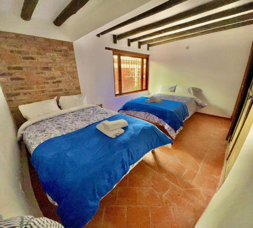 2 Betten in einem Zimmer mit blauer Bettwäsche in der Unterkunft Villa charlotte 3 en colombia in Villa de Leyva