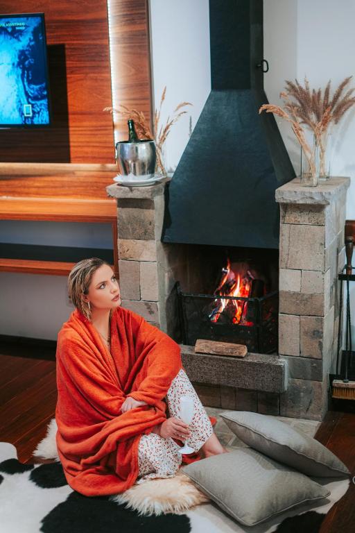 a woman sitting on the floor in front of a fireplace at Vila Suzana Parque Hotel in Canela