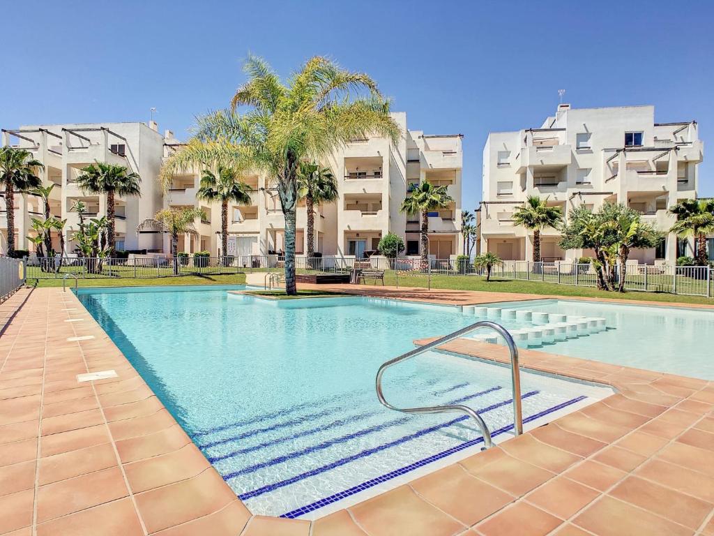 una gran piscina con palmeras y edificios de apartamentos en Las Terrazas de la Torre Golf Murcia, en Murcia