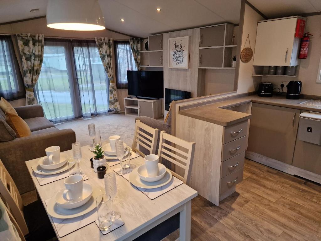 a kitchen and living room with a table and chairs at Bird Lake Pastures Holiday Caravan in Northampton