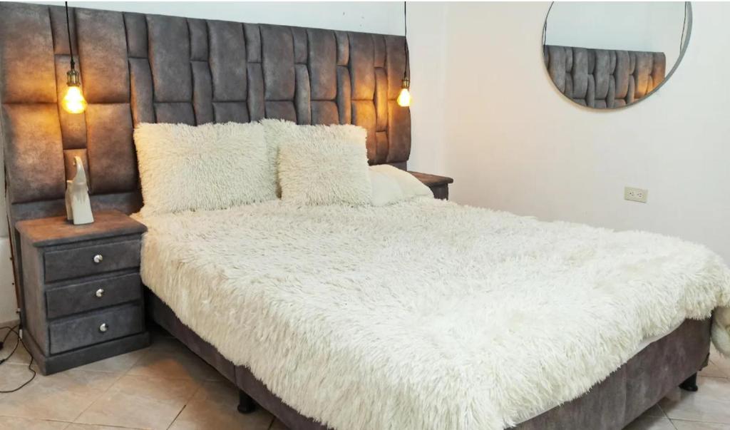 a bedroom with a large white bed with a wooden headboard at Habitacion cama doble en sabaneta in Sabaneta