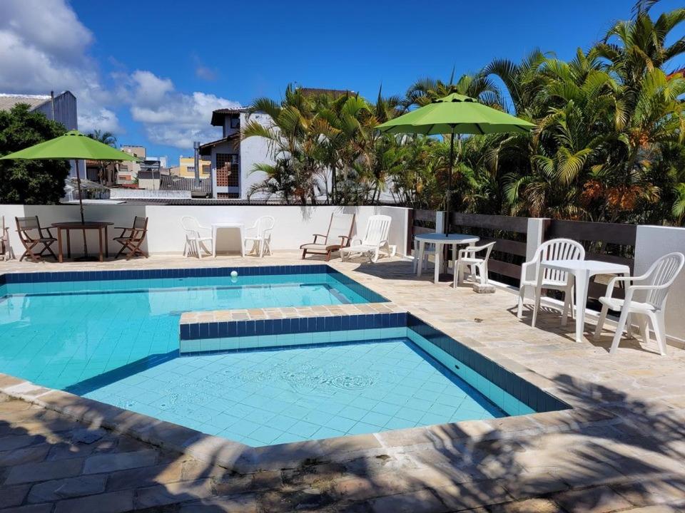 una piscina con sedie, tavolo e ombrellone di Canas Gold Praia Hotel a Florianópolis