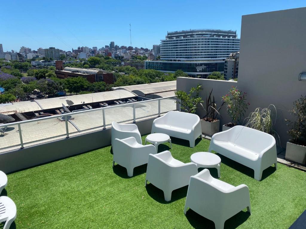 a patio with white chairs and grass on a roof at Estudio en Palermo Hollywood in Buenos Aires