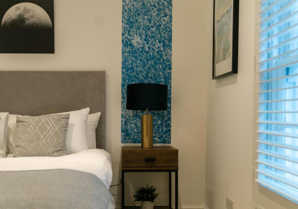 a bedroom with a bed and a lamp on a night stand at Stylish LUXE 4Beds Abbey Rd St Johns Wood in London