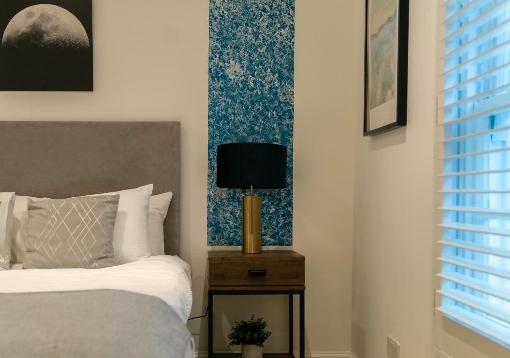 a bedroom with a bed and a lamp on a night stand at 4 Bedrooms Peaceful Home Abbey Rd - St Johns Wood in London
