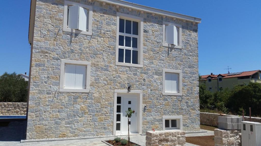 a stone house with white windows and a door at Apartments Rustic in Biograd na Moru