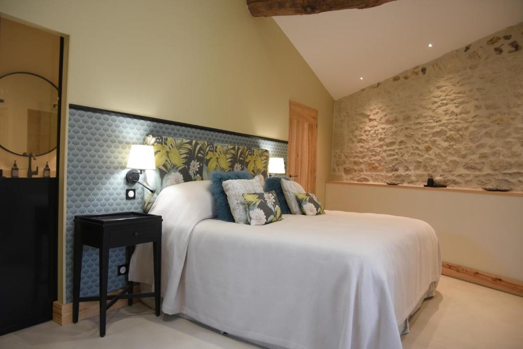 a bedroom with a large white bed with blue pillows at Girauderies Chambres d'Hotes/B+B in Floirac