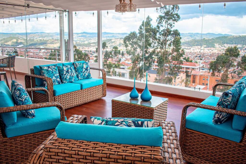 a living room with wicker furniture and a large window at Hermosa casa con lujoso rooftop en Cuenca in Cuenca