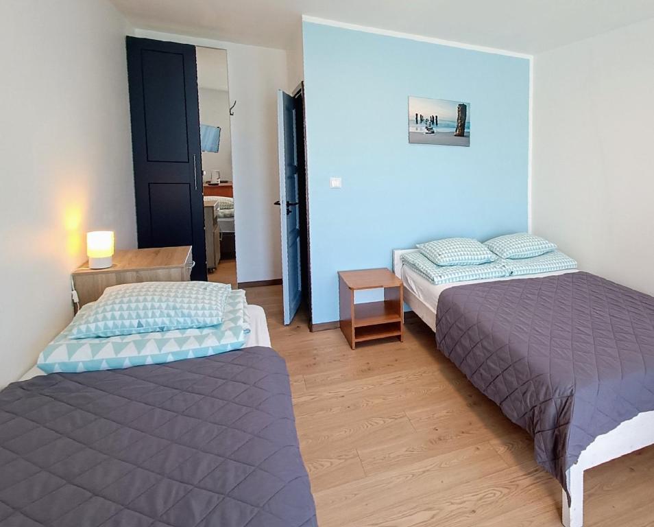 a bedroom with two beds and a room with a door at Pokoje Goscinne SALOMEA in Karwia