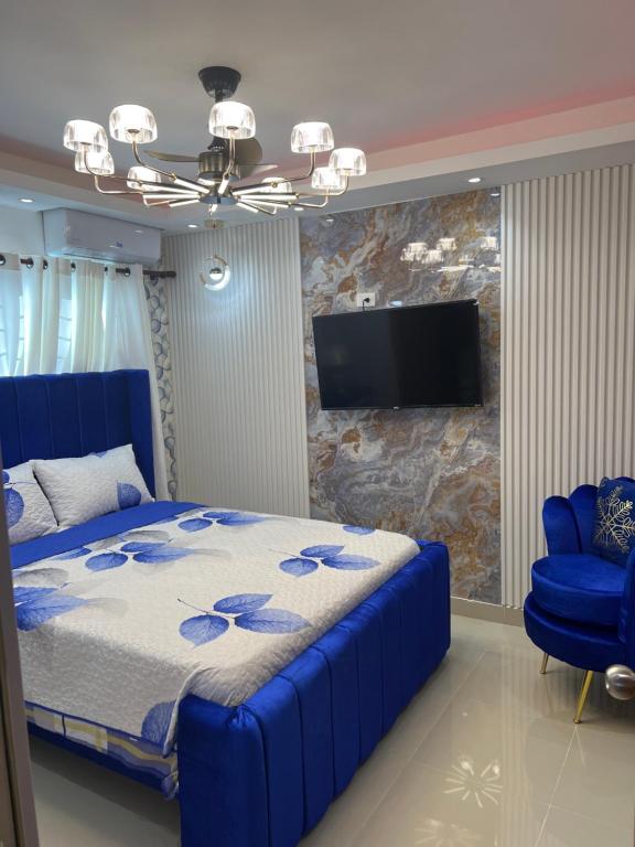 1 dormitorio con 1 cama azul y TV de pantalla plana en Coconut paradise Residences, 