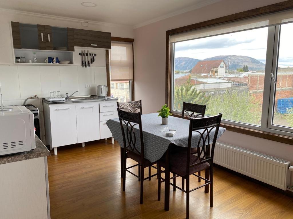 eine Küche mit einem Tisch und Stühlen sowie einem Fenster in der Unterkunft Patagonia Tower in Puerto Natales