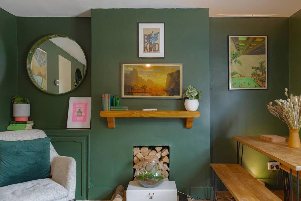 una sala de estar con una pared verde con chimenea en Stunning 2BD in the Heart of Malmesbury!, en Malmesbury