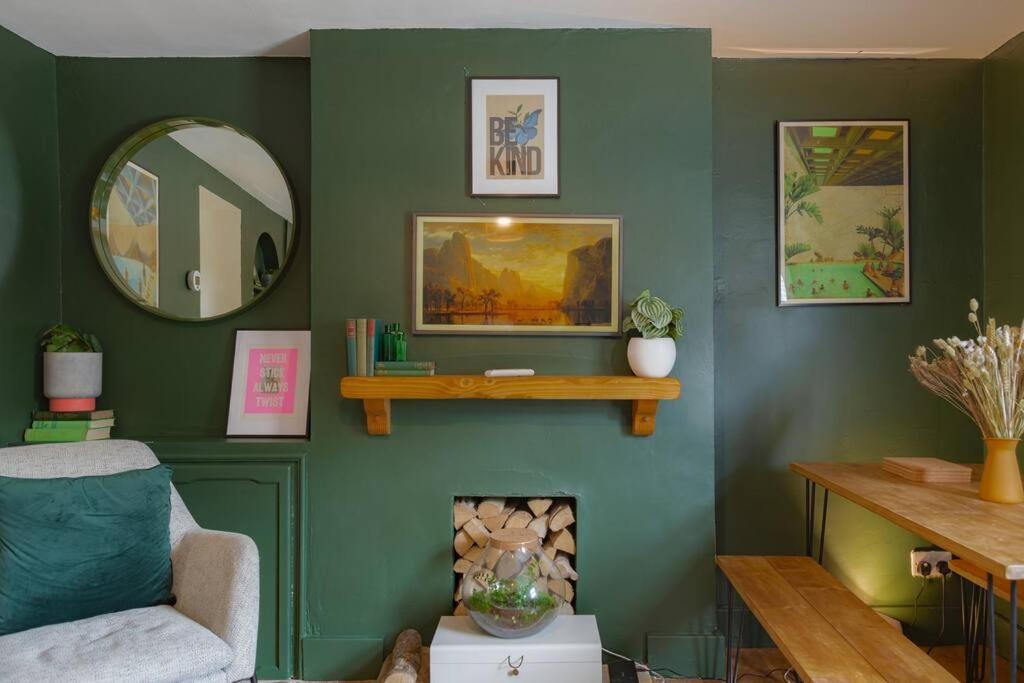 a living room with a green wall with a fireplace at Stunning 2BD in the Heart of Malmesbury! in Malmesbury