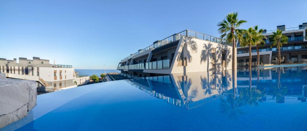 una piscina con palmeras y un edificio en Apartment in Gran Alacant with Sea View, AC, pool en Gran Alacant