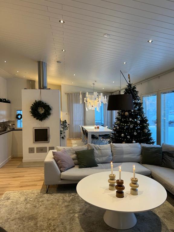 a living room with a couch and a christmas tree at Arctic Circle Home for Winter Holiday in Rovaniemi