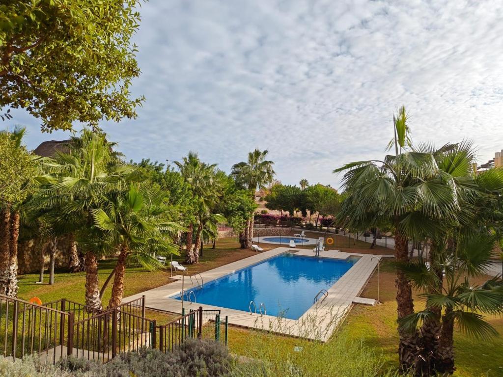 una piscina en un parque con palmeras en Private Apartment & Pool - El Oasis Golf Resort - Fuente del Alamo, en Murcia