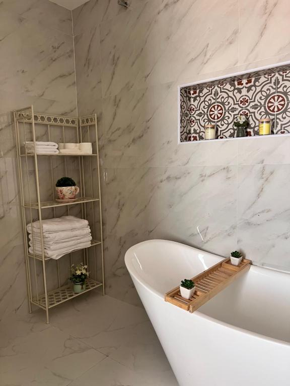 アル・アインにあるMarbella Resortの白いバスタブと大理石の壁が備わるバスルーム