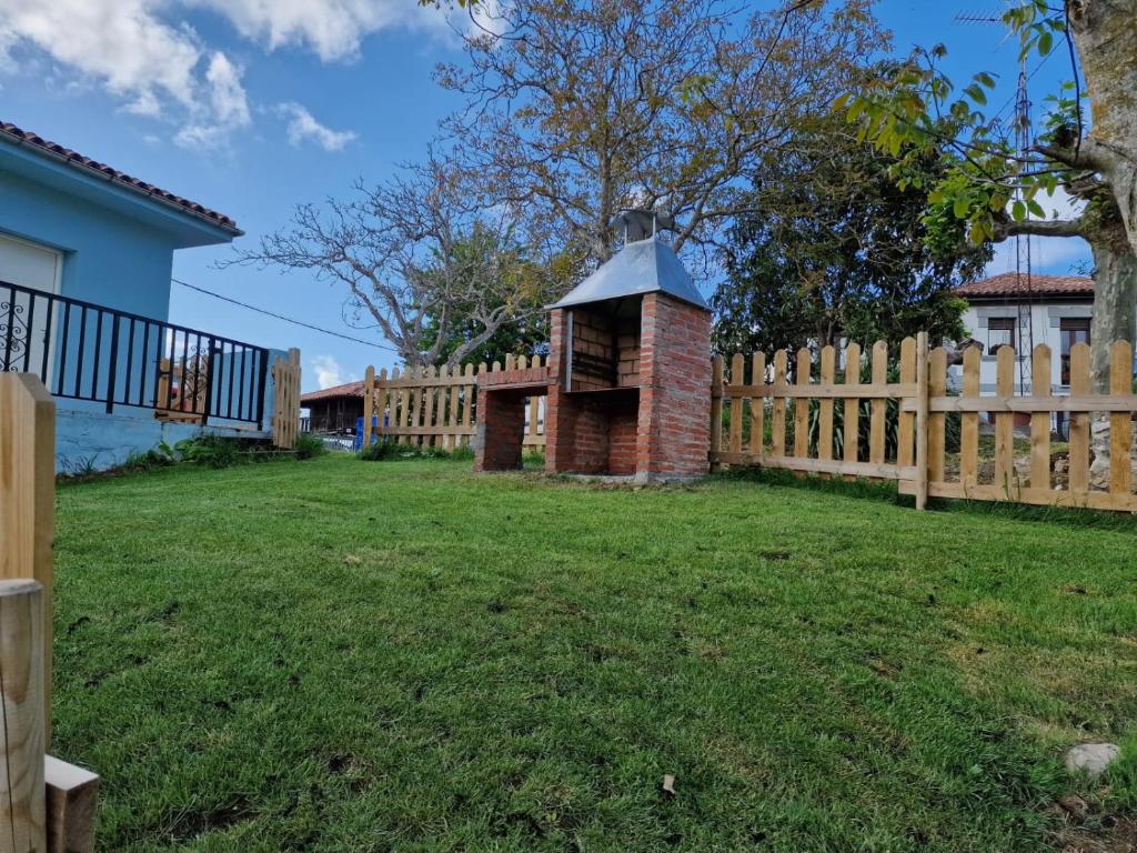 a wooden fence with a brick chimney in a yard at vivienda vacacional casa tames in Ribadesella