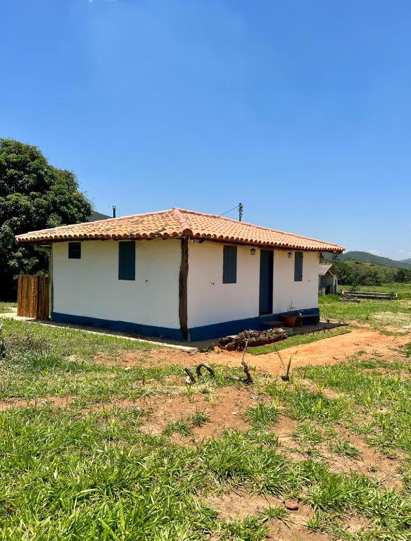 una casa blanca con techo rojo en un campo en Luna Tiny House Mineira en Capitólio