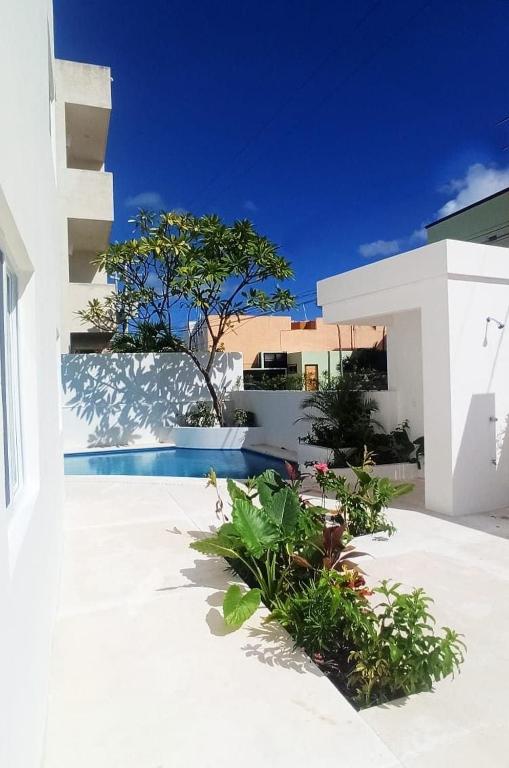 a white building with a swimming pool in a yard at Edifico con departamentos amplios cerca de la playa in Puerto Morelos