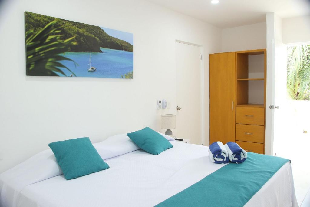una camera da letto con un letto bianco con cuscini blu di Edifico con departamentos amplios cerca de la playa a Puerto Morelos