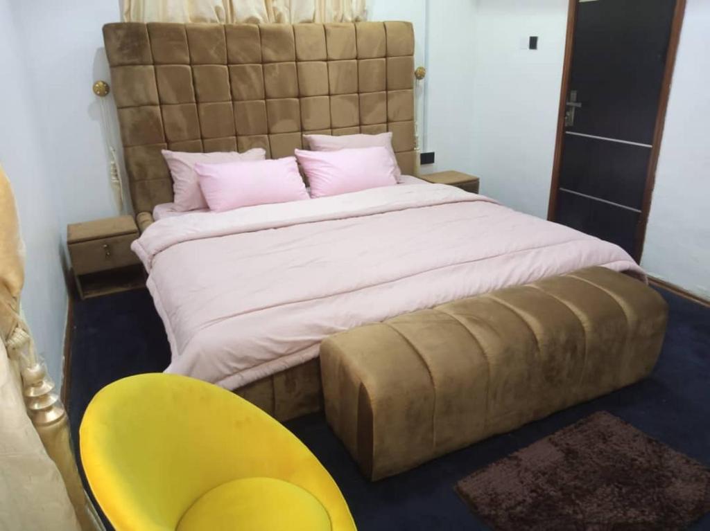 a bedroom with a large bed and a yellow chair at cozy comforts in Lagos