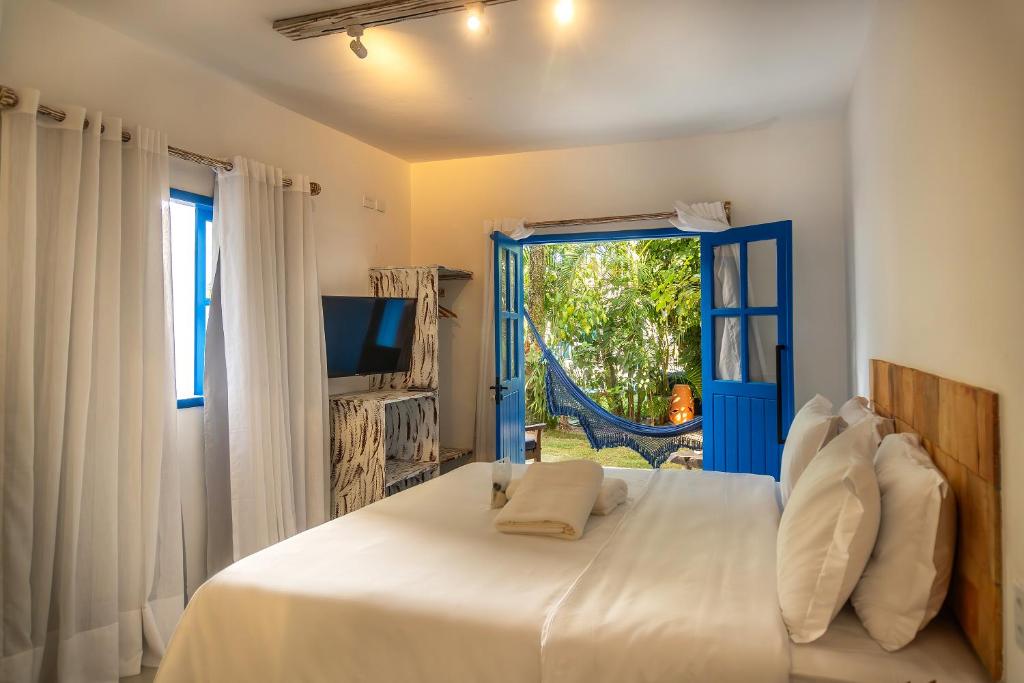 a bedroom with a white bed and a blue door at Awe Villa Boutique Trancoso in Trancoso